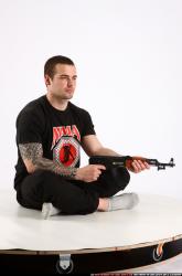 Man Adult Athletic White Fighting with submachine gun Sitting poses Sportswear